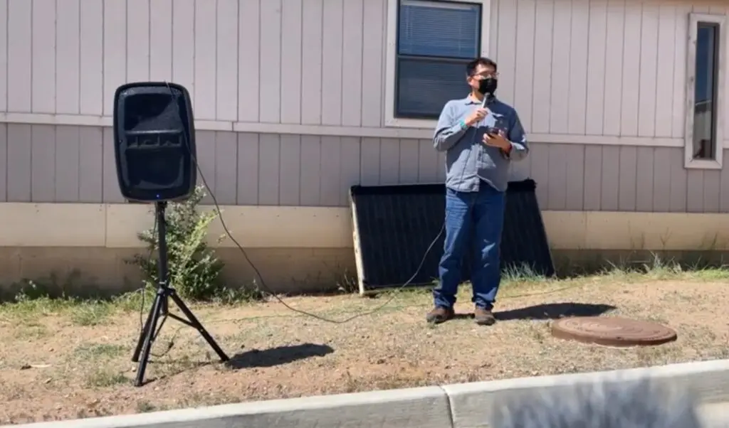 A man standing in front of a house with a microphone.