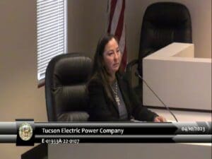 A woman is sitting at a desk in front of a microphone.