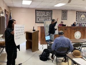 A group of people in a room with a sign in front of them.