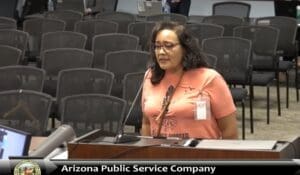 A woman standing at a podium in front of a group of people.