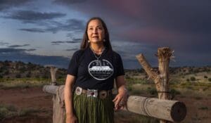 A woman in a t - shirt standing next to a fence.