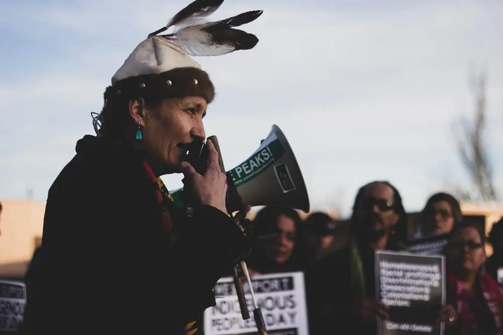 A woman holding a megaphone in front of a crowd of people.