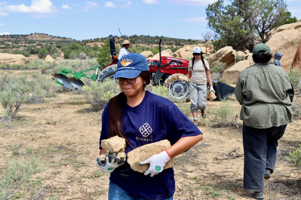 Scholars lifting and gathering rocks with TNA crew members.