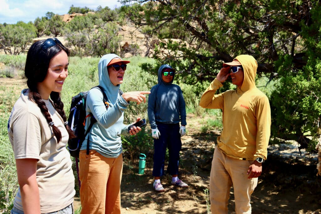 Scholars and Audrey Kruze chatting with Andrew Atencia in the field.