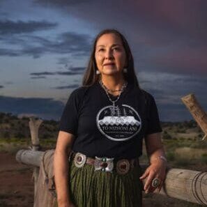 A woman wearing a t - shirt standing in front of a fence.
