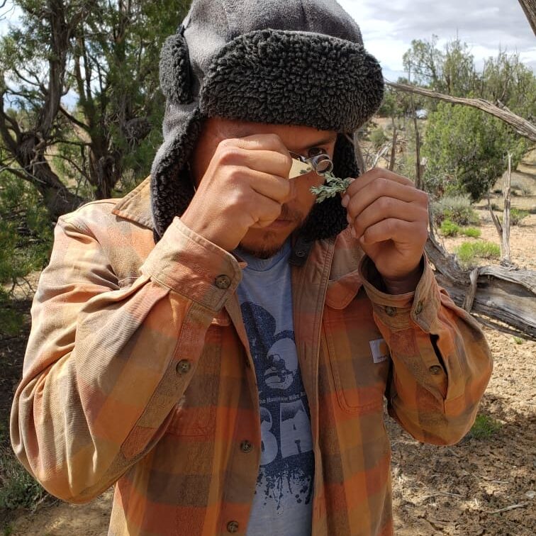 A man in a plaid hat is putting on a hat.
